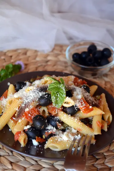 Deliciosa comida italiana penne ala puttanesca en un plato sobre una mesa . — Foto de Stock