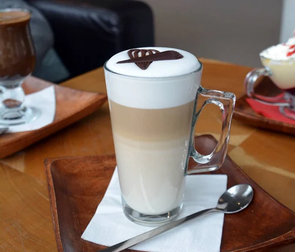 Latte macchiato em uma xícara de vidro em uma placa de madeira — Fotografia de Stock