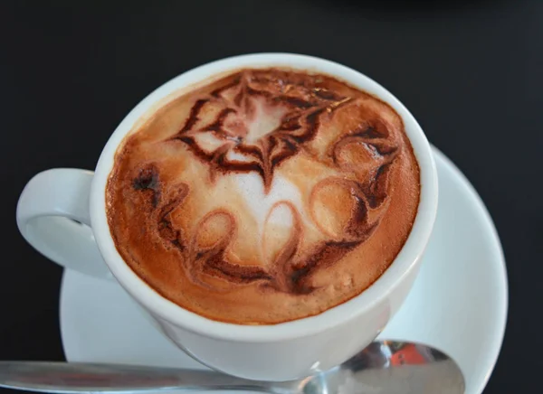 Xícara de cappuccino espumoso em uma mesa preta . — Fotografia de Stock