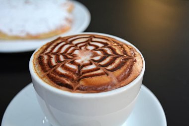 Siyah bir tabloda köpüklü kapuçino fincan.