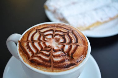 Siyah bir tabloda köpüklü kapuçino fincan.