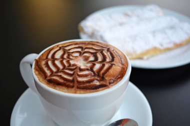 Siyah bir tabloda köpüklü kapuçino fincan.