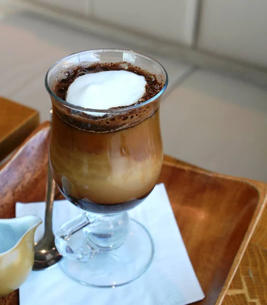 Café negro con leche en una taza de vidrio sobre una mesa de madera —  Fotos de Stock