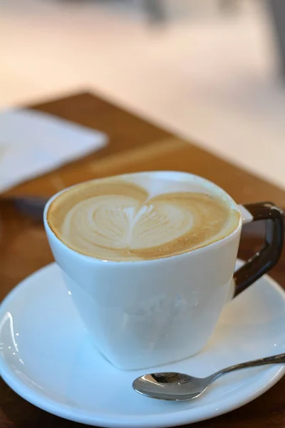 Köstlicher schäumender Cappuccino auf einer weißen Tasse auf einem Teller. — Stockfoto