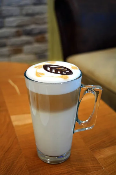 Latte Macchiato sur une tasse en verre sur une table en bois . — Photo