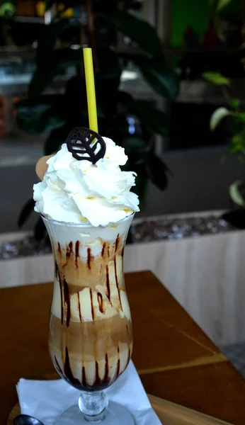 Delicious iced coffee with whipped cream on a glass cup.