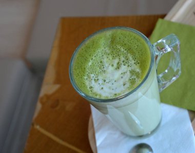 Ahşap bir masa cam bardakta Matcha latte yeşil çayı.