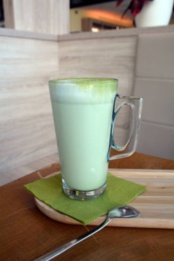 Ahşap bir masa cam bardakta Matcha latte yeşil çayı.
