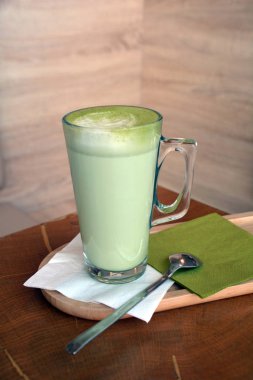 Ahşap bir masa cam bardakta Matcha latte yeşil çayı.