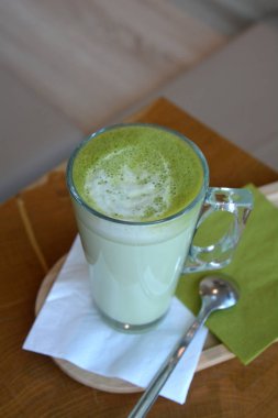 Ahşap bir masa cam bardakta Matcha latte yeşil çayı.