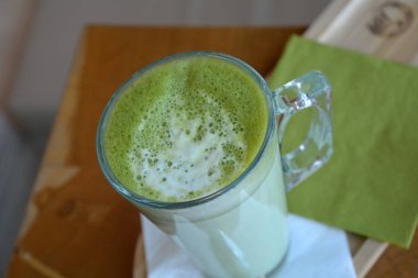 Ahşap bir masa cam bardakta Matcha latte yeşil çayı.