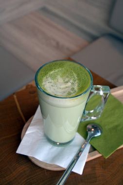 Ahşap bir masa cam bardakta Matcha latte yeşil çayı.