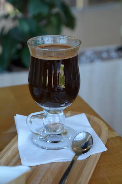 Caffè nero con latte su una tazza di vetro su un tavolo di legno . — Foto Stock