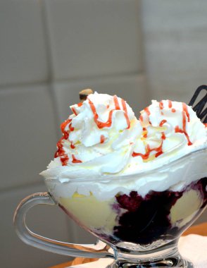 Vanilyalı dondurma ve bir cam kase krem şanti ile sıcak yaban mersini.