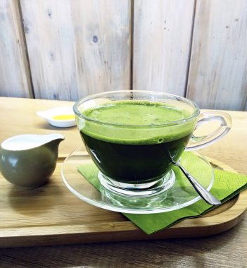 Sıcak sütle kibrit yeşil çay, cam bir bardakta, ahşap tabakta..