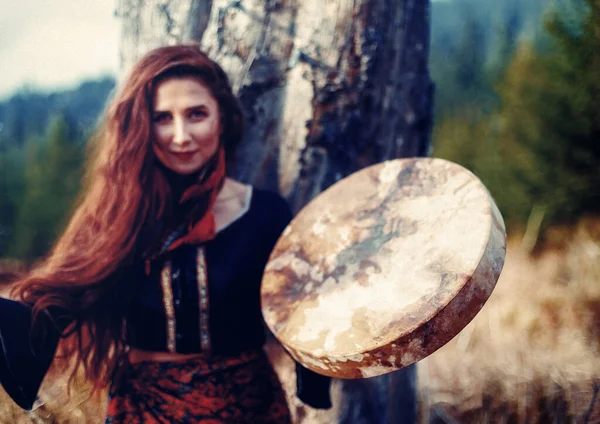 Mooi sjamanistisch meisje spelen op sjamaan frame drum in de natuur. — Stockfoto