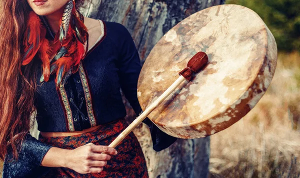 Bela garota xamânica jogando no tambor quadro xamã na natureza. — Fotografia de Stock