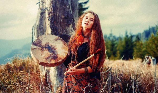 Hermosa chica chamánica jugando en tambor marco chamán en la naturaleza. — Foto de Stock