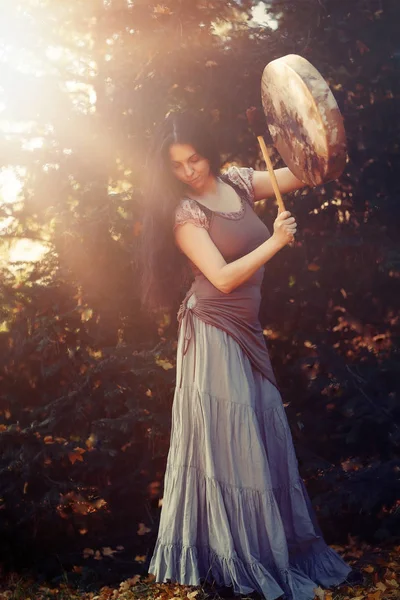 Beautiful shamanic girl playing on shaman frame drum in the nature. — Stock Photo, Image