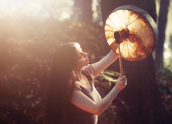 Όμορφο σαμανικό κορίτσι παίζει σε σαμάνο πλαίσιο τύμπανο στη φύση. — Φωτογραφία Αρχείου