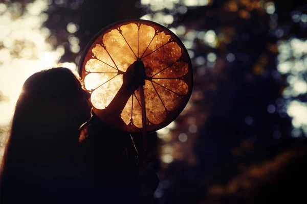 Hermosa chica chamánica jugando en tambor marco chamán en la naturaleza. —  Fotos de Stock