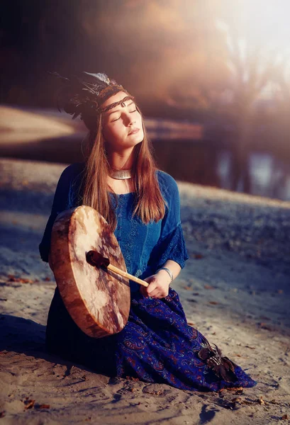 Bella ragazza sciamanica che gioca sul tamburo telaio sciamano nella natura. — Foto Stock