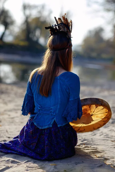 Beautiful shamanic girl playing on shaman frame drum in the nature. — Stock Photo, Image