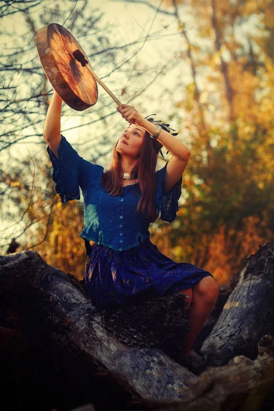 Hermosa chica chamánica jugando en tambor marco chamán en la naturaleza. — Foto de Stock