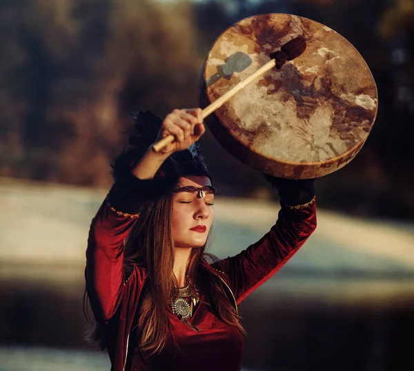 Beautiful shamanic girl playing on shaman frame drum in the nature. — Stock Photo, Image