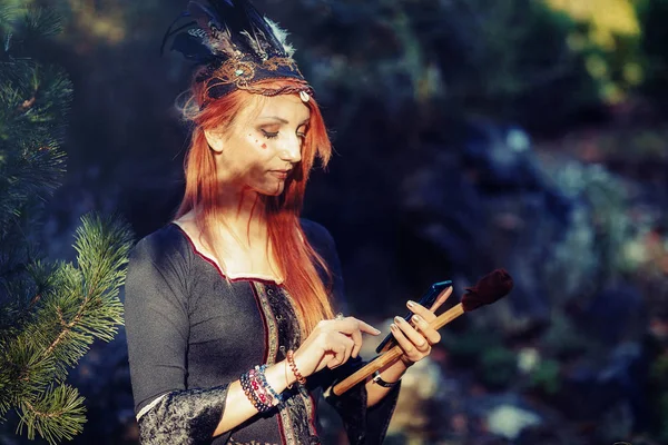 Beautiful shamanic woman with headband and cell phone in the nature. — Stock Photo, Image