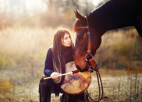 馬とシャーマンのフレームドラムを持つ少女は. — ストック写真