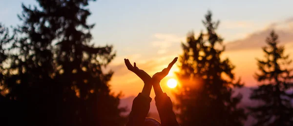 Sole nelle mani. Tramonto sullo sfondo delle mani alzate . — Foto Stock