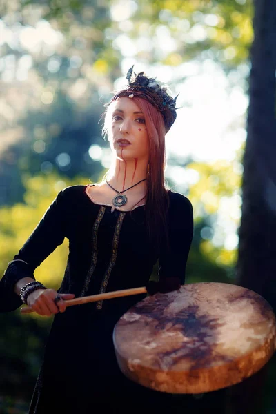 Krásná šamanská dívka hraje na šaman rám buben v přírodě. — Stock fotografie