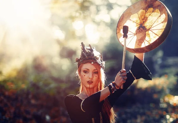 Beautiful shamanic girl playing on shaman frame drum in the nature. — Stock Photo, Image