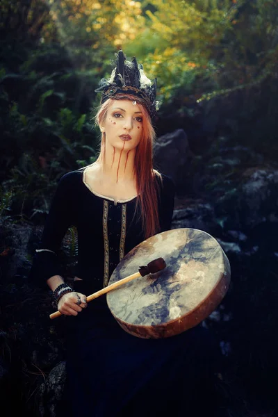 Beautiful shamanic girl playing on shaman frame drum in the nature. — Stock Photo, Image