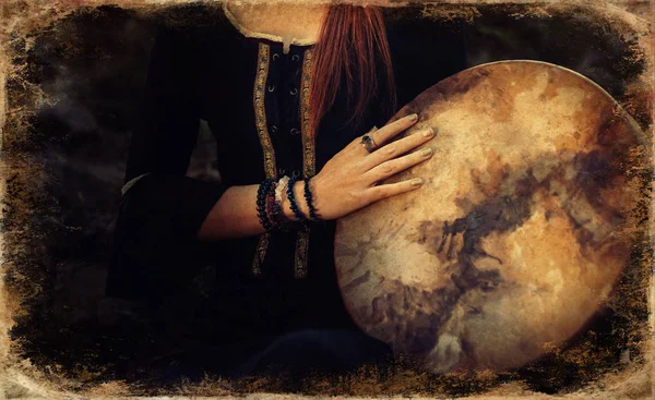 Beautiful shamanic girl playing on shaman frame drum in the nature, old photo effect. — Stock Photo, Image