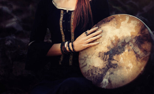 красивая шаманская девушка, играющая на барабане шамана на природе.