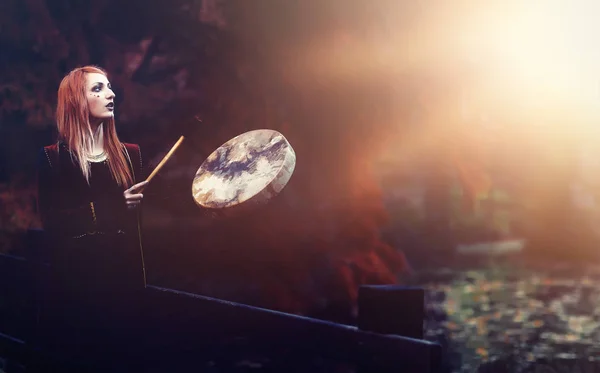 Beautiful shamanic girl playing on shaman frame drum in the nature. — Stock Photo, Image