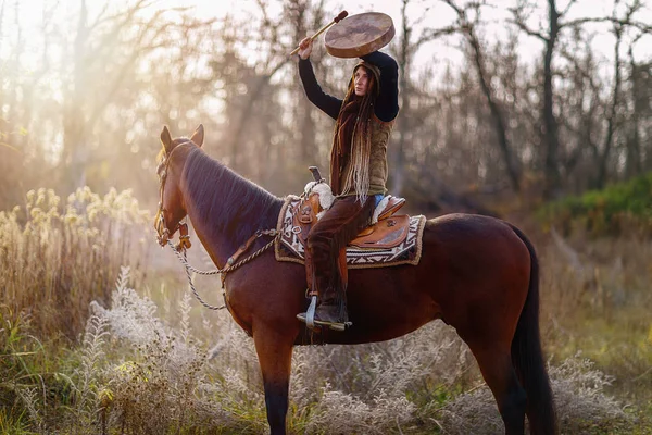 Young dreadded girl with her horse and shamanic frame drum. — Stock Photo, Image