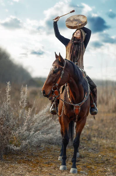 Молодая страшная девушка со своей лошадью и шаманским барабаном. — стоковое фото