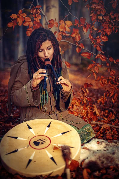 Dreadlocks woman in forest, with double flute and shaman drum. — Stock Photo, Image