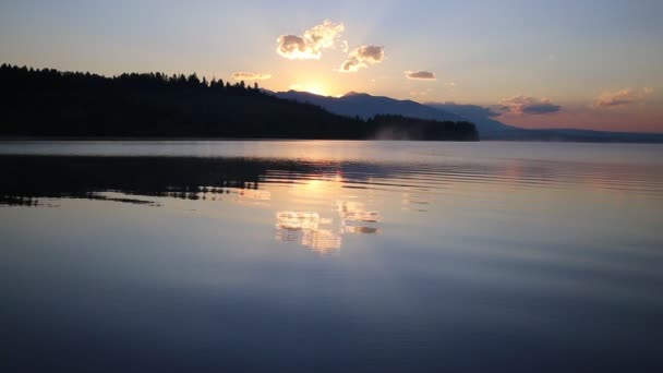 Bela paisagem com montanhas e lago ao amanhecer em tons dourados, azuis e roxos . — Vídeo de Stock