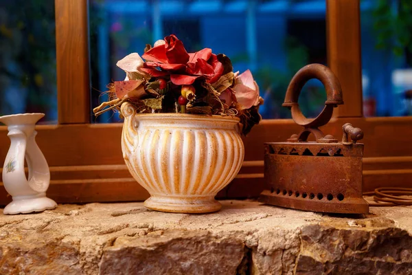 Ferro velho e vaso com flores na janela . — Fotografia de Stock