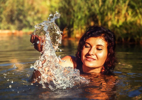 Schöne Frau im See spritzt Wasser und Maleffekt. — Stockfoto