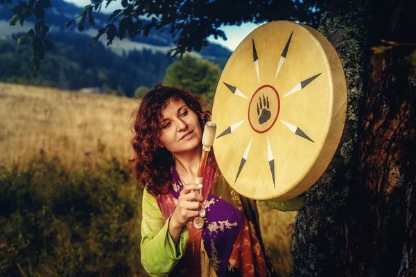 Piękna szamanka dziewczyna gra na szaman ramki bęben w przyrodzie. — Zdjęcie stockowe