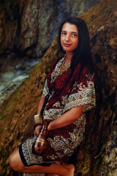 Mulher com carafe em belo vestido oriental na água . — Fotografia de Stock