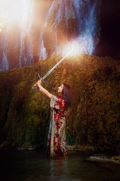 Femme avec épée dans le lac près de la cascade. — Photo