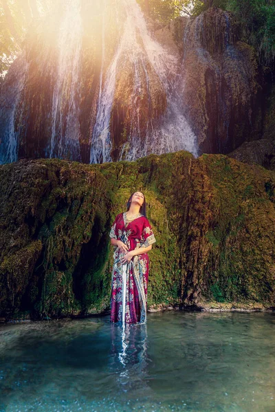 Mujer con espada en el lago cerca de la cascada. —  Fotos de Stock