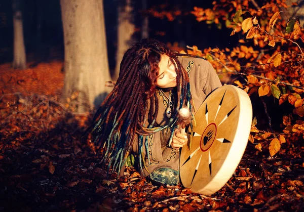 Hermosa chica chamánica jugando en tambor marco chamán en la naturaleza. — Foto de Stock