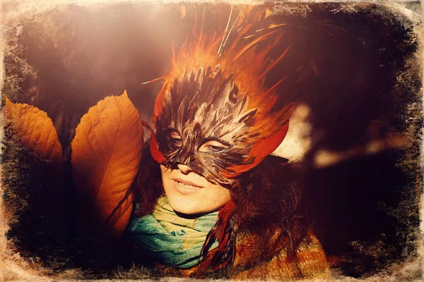 Young woman with a colorful feather face mask, old photo effect. — Stock Photo, Image